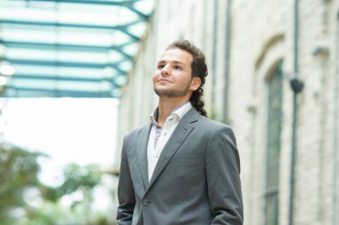 Genç ve başarılı bir iş adamı akıllı telefon kullanarak dışarıda çalışıyor. Sıradan giysili bir adam. İş, serbest meslek ve uzak çalışma.