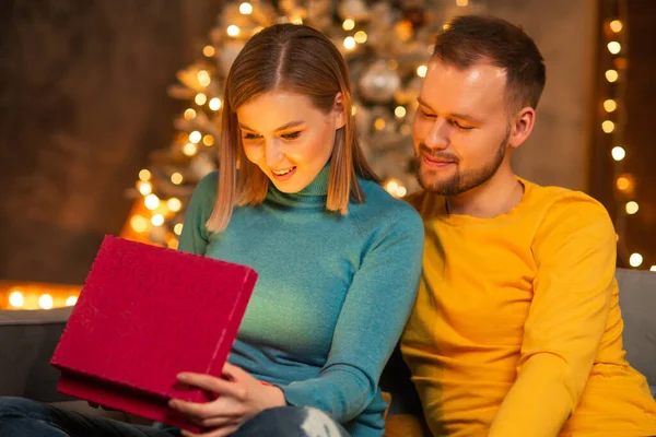 Pareja joven y cariñosa celebrando la Navidad en casa. Joven y su atractiva novia en el interior de una casa con un árbol de Navidad. —  Fotos de Stock
