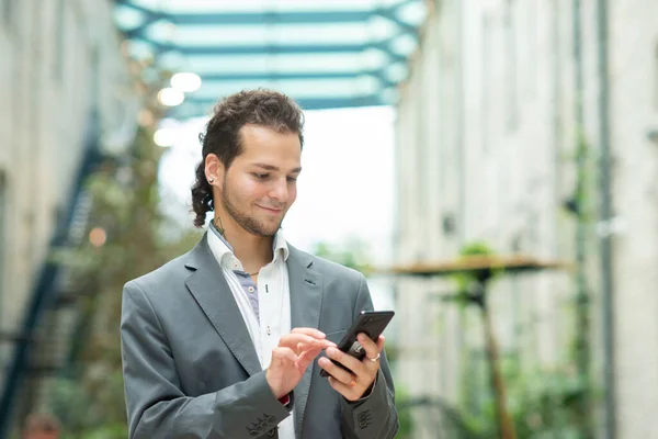 Ein junger erfolgreicher Geschäftsmann arbeitet im Freien mit dem Smartphone. Mann in Freizeitkleidung. Unternehmen, Freiberufler und Fernarbeit. — Stockfoto