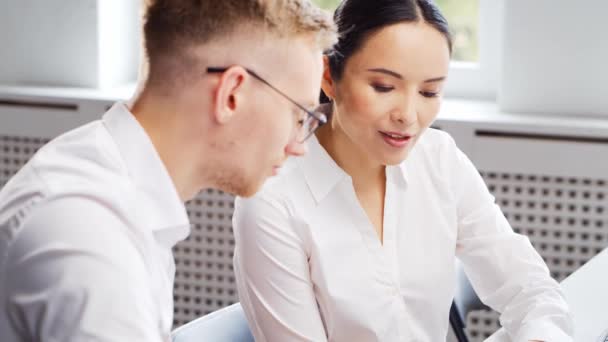 Um especialista sênior e um funcionário júnior estão sentados à mesa e discutindo questões de trabalho. Um homem e uma mulher estão a trabalhar no escritório. O conceito de negócio, trabalho em equipe e resolução de problemas. — Vídeo de Stock