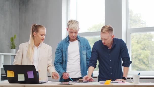 El equipo de jóvenes startups está trabajando en la mesa de la oficina, discutiendo la estrategia y el plan de desarrollo de la empresa. Negocios, innovación, lluvia de ideas y trabajo en equipo. — Vídeos de Stock