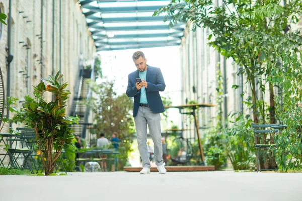 Un giovane uomo d'affari di successo sta lavorando all'aperto utilizzando lo smartphone. Uomo con un abbigliamento casual. Affari, freelance e lavoro a distanza. — Foto Stock
