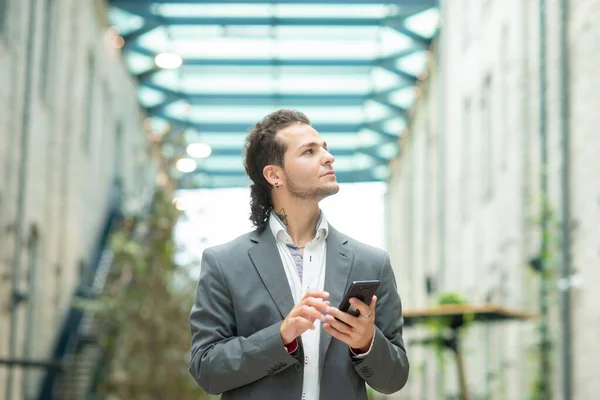 Ein junger erfolgreicher Geschäftsmann arbeitet im Freien mit dem Smartphone. Mann in Freizeitkleidung. Unternehmen, Freiberufler und Fernarbeit. — Stockfoto
