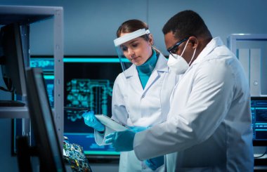 Bir grup mikro elektronik mühendisi modern bir mikroişlemci laboratuvarında tartışıyorlar. Elektronik tasarımcıların işyeri. Yenilikler ve icatlar kavramı.