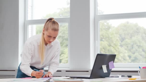 프리랜서 직원의 직장 또는 가정 사무실의 여학생. 젊은 여자는 컴퓨터와 그 밖의 장치를 사용하여 일합니다. 원격 직업 개념. — 비디오