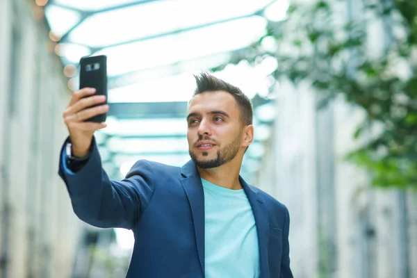 A young successful businessman is working outdoor using smartphone. Man in a casual wear. Business, freelance and remote work. — Stock Photo, Image