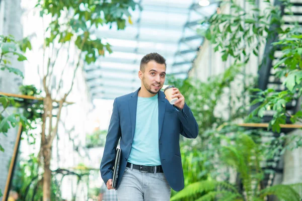 Un joven empresario exitoso está caminando por la calle. Un hombre con ropa casual. Negocios, freelance y trabajo remoto. —  Fotos de Stock