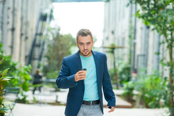 Молодой успешный бизнесмен работает на открытом воздухе с помощью смартфона. Человек в повседневной одежде. Бизнес, фриланс и удаленная работа. — стоковое фото