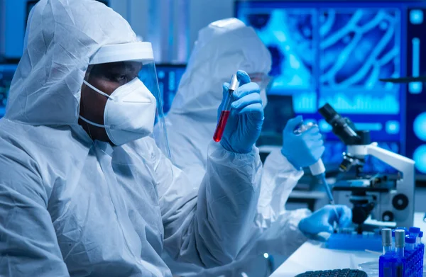 O médico afro-americano de fato protector está a fazer experiências científicas e a desenvolver vacinas num laboratório moderno. Assistente de laboratório. O conceito de ciência e medicina. — Fotografia de Stock