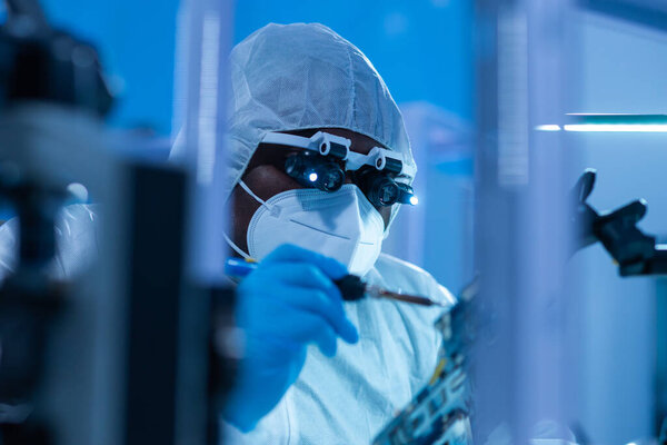 Афроамериканский ученый работает в современной научной лаборатории по исследованию и разработке микроэлектроники и процессоров. Производственный работник использует компьютерные технологии и оборудование.