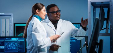 Bir grup mikro elektronik mühendisi modern bir mikroişlemci laboratuvarında tartışıyorlar. Elektronik tasarımcıların işyeri. Yenilikler ve icatlar kavramı.