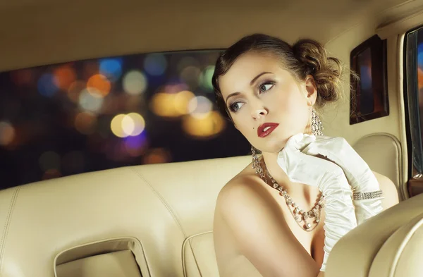 Beautiful and rich superstar girl sitting in a retro car — Stock Photo, Image