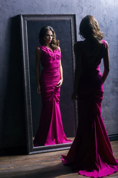 Kobieta w długiej sukni w pobliżu lustro — Zdjęcie stockowe
