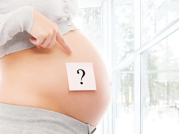 Pregnant belly with sticker with question — Stock Photo, Image