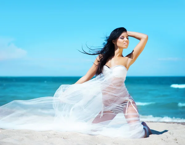 Mulher posando com seda soprando na praia — Fotografia de Stock