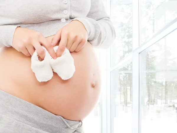 Pregnant belly with baby shoes — Stock Photo, Image