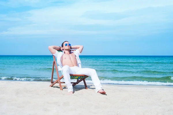Hombre guapo escalofriante en silla de playa — Foto de Stock