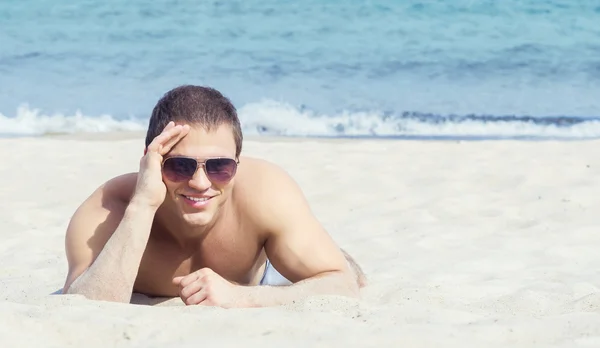 Man in sunglasses lying on beach — Stock Photo, Image