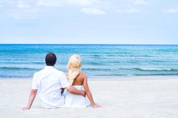 Couple sitting and embracing on beach — Stock Photo, Image