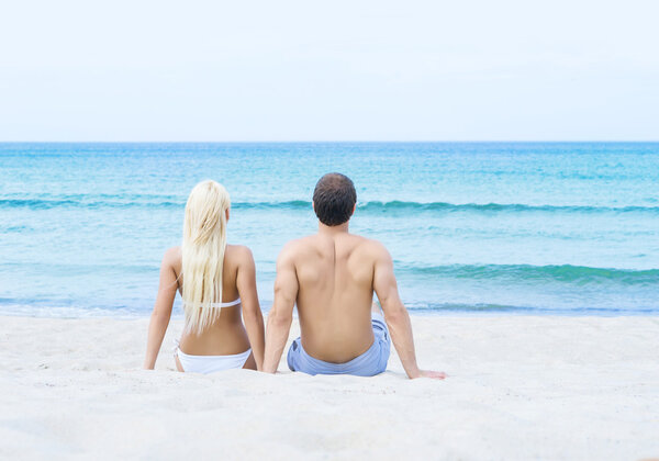 man and woman sitting on summer beach