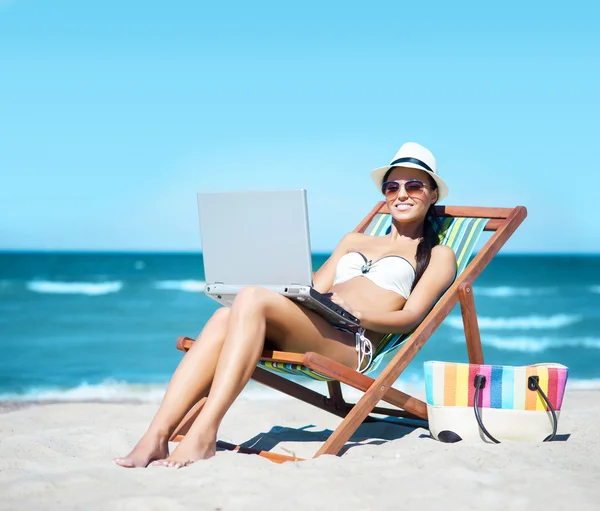Женщина с ноутбуком отдыхает на пляже — стоковое фото