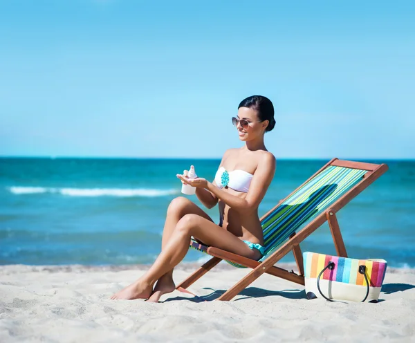 Donna che utilizza crema abbronzante sulla spiaggia — Foto Stock