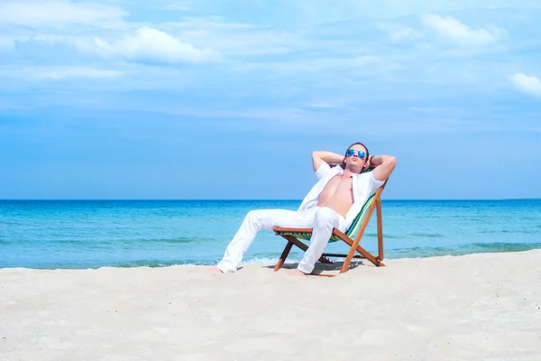 Man zit op strandstoel op strand — Stockfoto