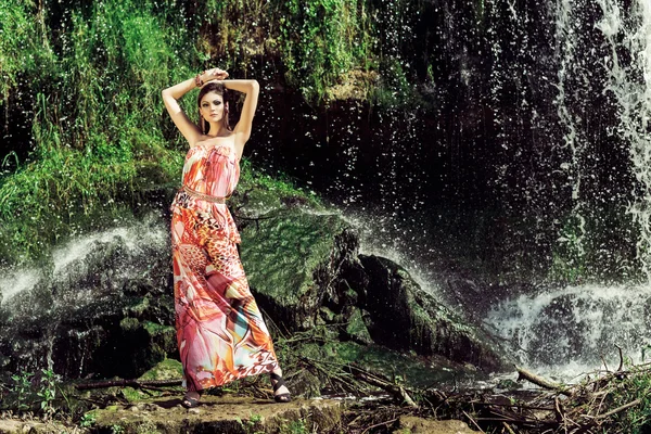 滝の前でポーズするドレスを着た女性 — ストック写真