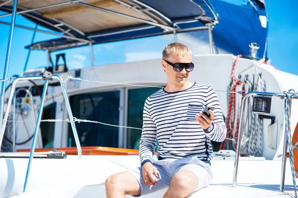 Homem jovem e bonito em um barco à vela — Fotografia de Stock