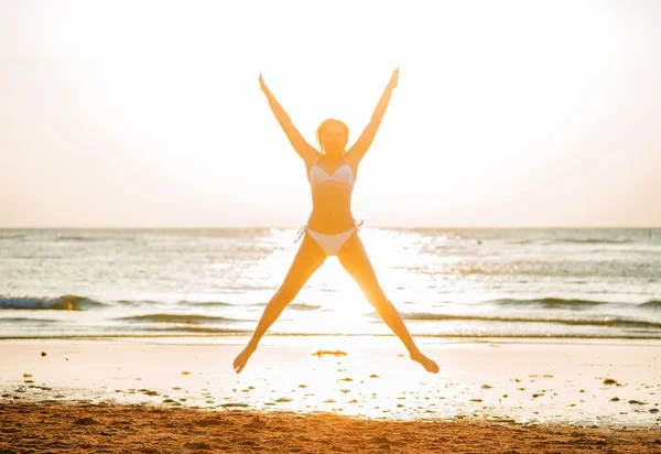 Vacker kvinna hoppar på stranden — Stockfoto