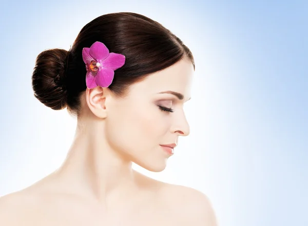 Здоровая женщина с цветком орхидеи в волосах — стоковое фото