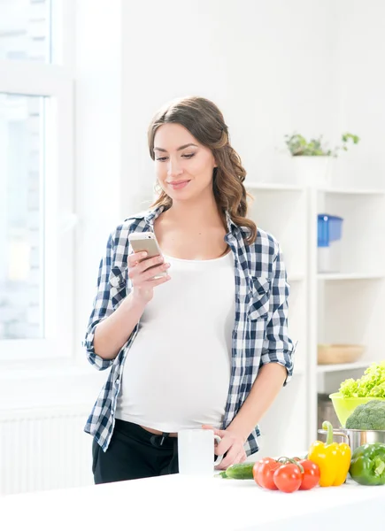 Zwangere lachende vrouw surfen smartphone — Stockfoto