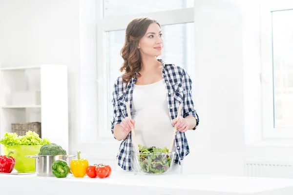 Mujer embarazada mezclando ensalada — Foto de Stock