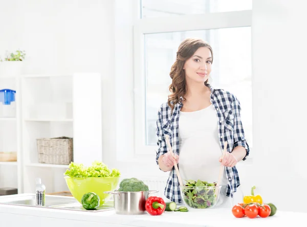 Mujer embarazada mezclando ensalada — Foto de Stock