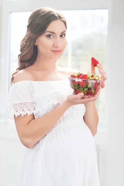 Zwangere vrouw met kom van aardbeien. — Stockfoto