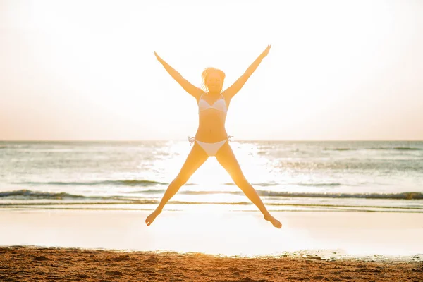 Vrouw springen op strand — Stockfoto