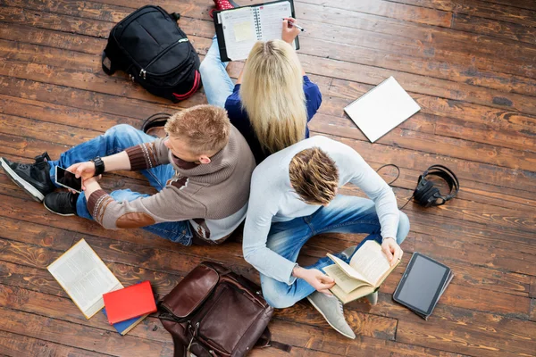 Gruppo di studenti seduti sul pavimento in legno — Foto Stock