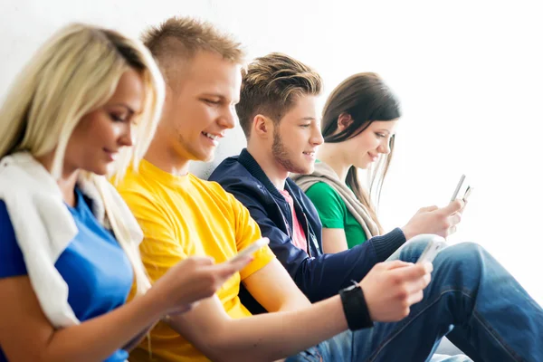 Studenter på rast med smartphones — Stockfoto