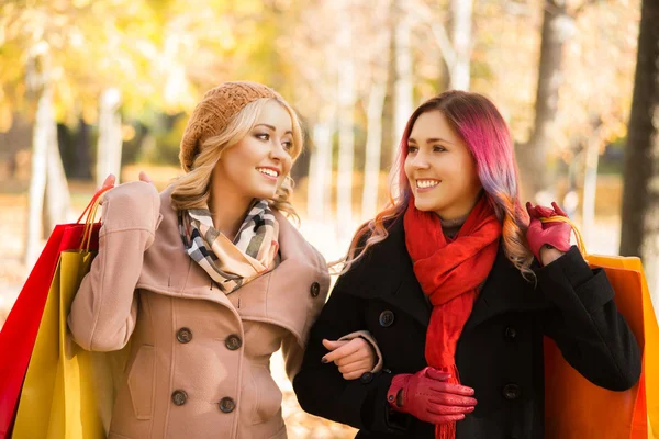 Two girls having a pleasant talk while walking the autumn park. — Stock Photo, Image