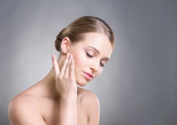 Attractive girl touching her smooth skin over cheeks on grey background. — Stock Photo, Image