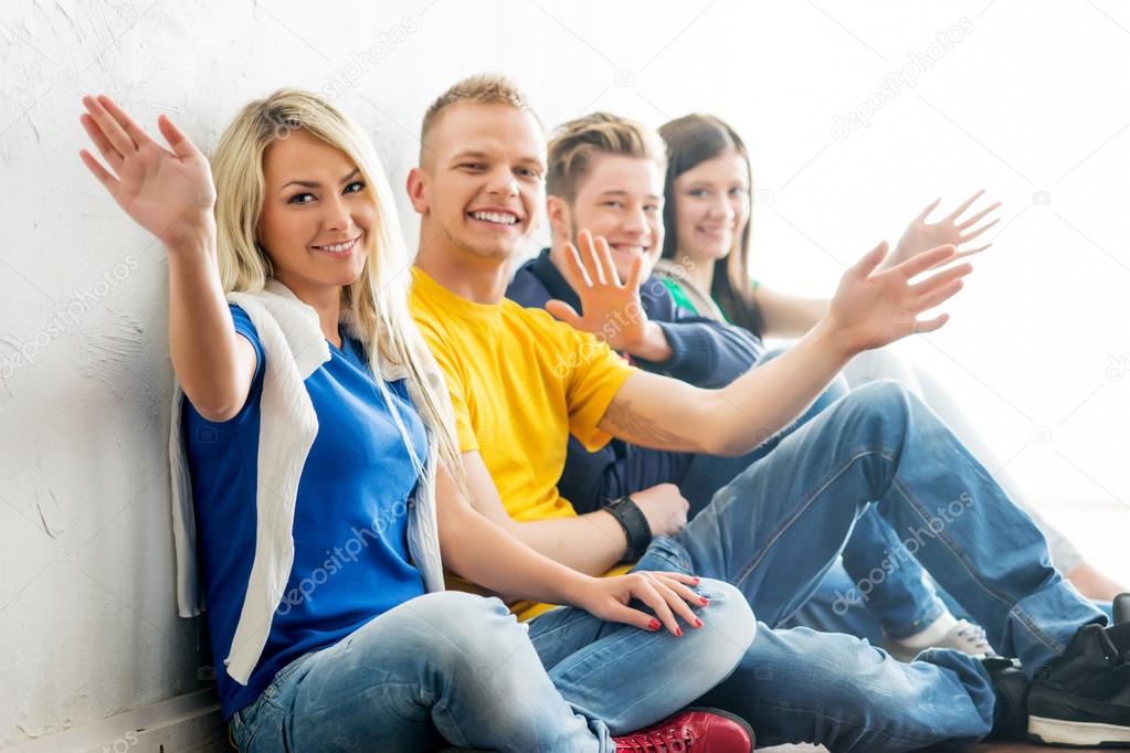 Group of happy students on a break waving. Focus on a boy and a girl.