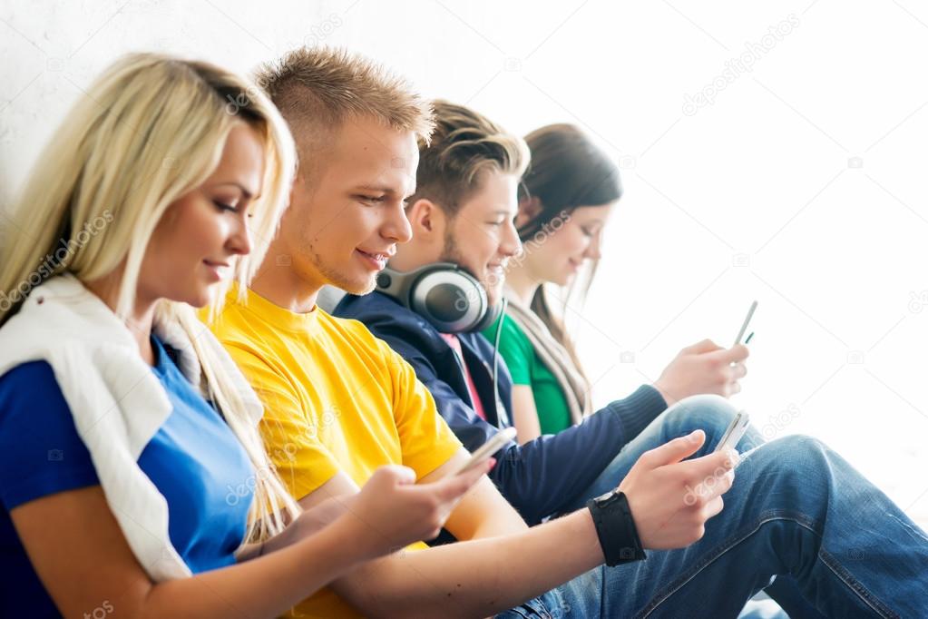 Group of students on a break. Focus on a boy using smartphone.