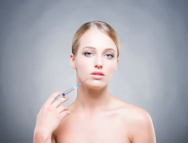 Mulher jovem com seringa injetando botox na pele lisa . — Fotografia de Stock
