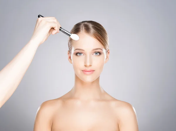 Menina bonita está sendo aplicada com cosméticos — Fotografia de Stock