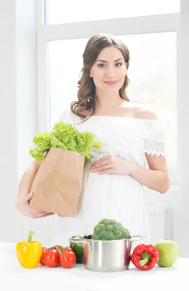 Beautiful pregnant woman with a shopping bag in the kitchen — Stock Photo, Image