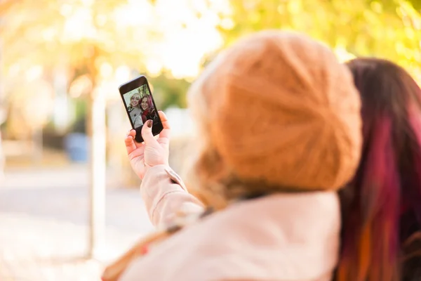 Zwei Mädchen machen Selfies im Herbstpark — Stockfoto