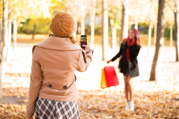 Duas mulheres tirando fotos no outono depois de fazer compras — Fotografia de Stock