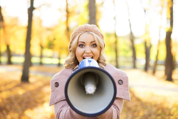 Woman yelling with loudspeaker in autumn park — Stock Photo, Image