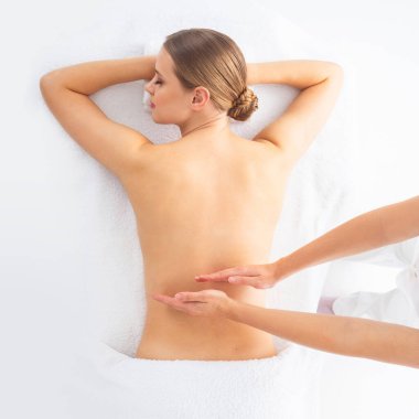 Beyaz arka planda masaj yaptıran genç bir kadın. Spa, sağlık ve dinlenme konsepti.