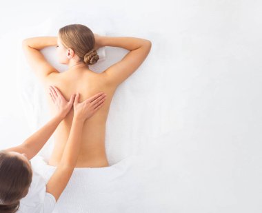 Beyaz arka planda masaj yaptıran genç bir kadın. Spa, sağlık ve dinlenme konsepti.